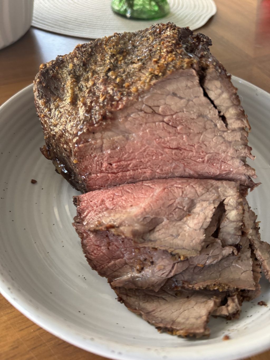 The finished beef roast, partially sliced on a white plate.