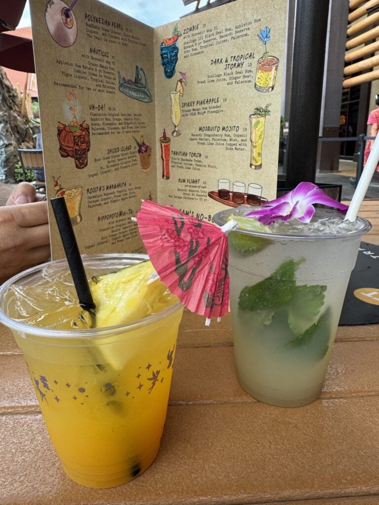 Two cocktails in front of the Tiki Drink Menu