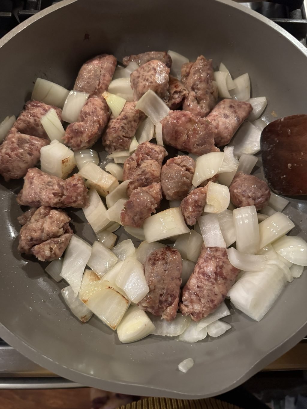 Onions and sausage cooking in a skillet