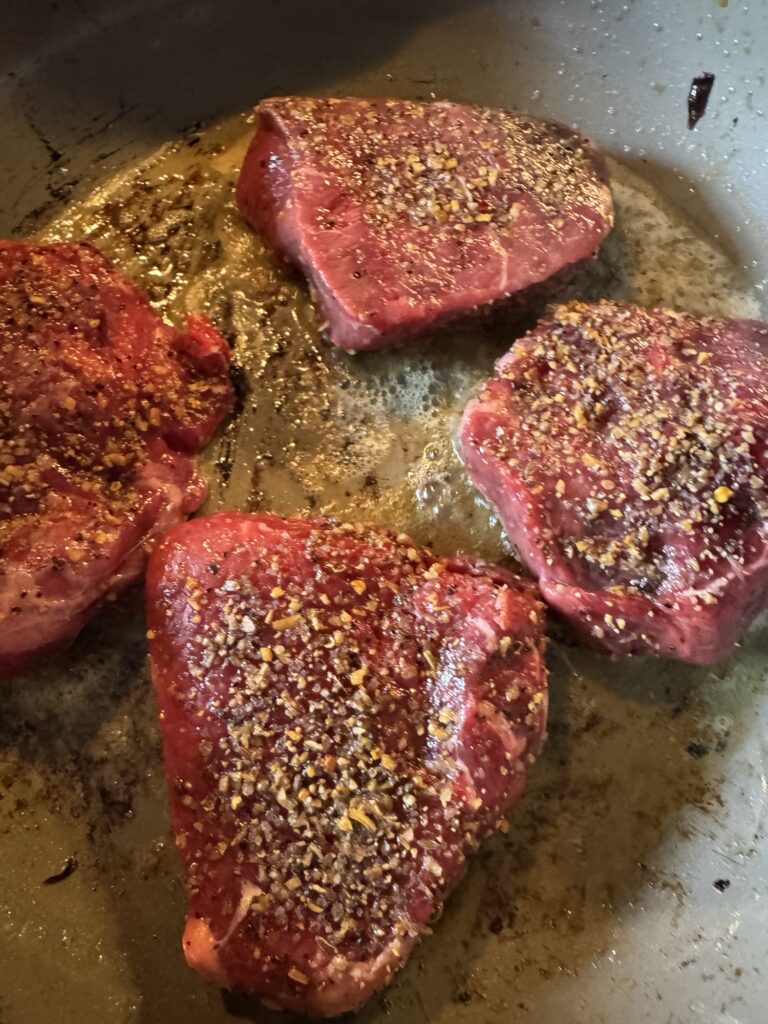 Seasoned sirloin medallions cooking in the pan