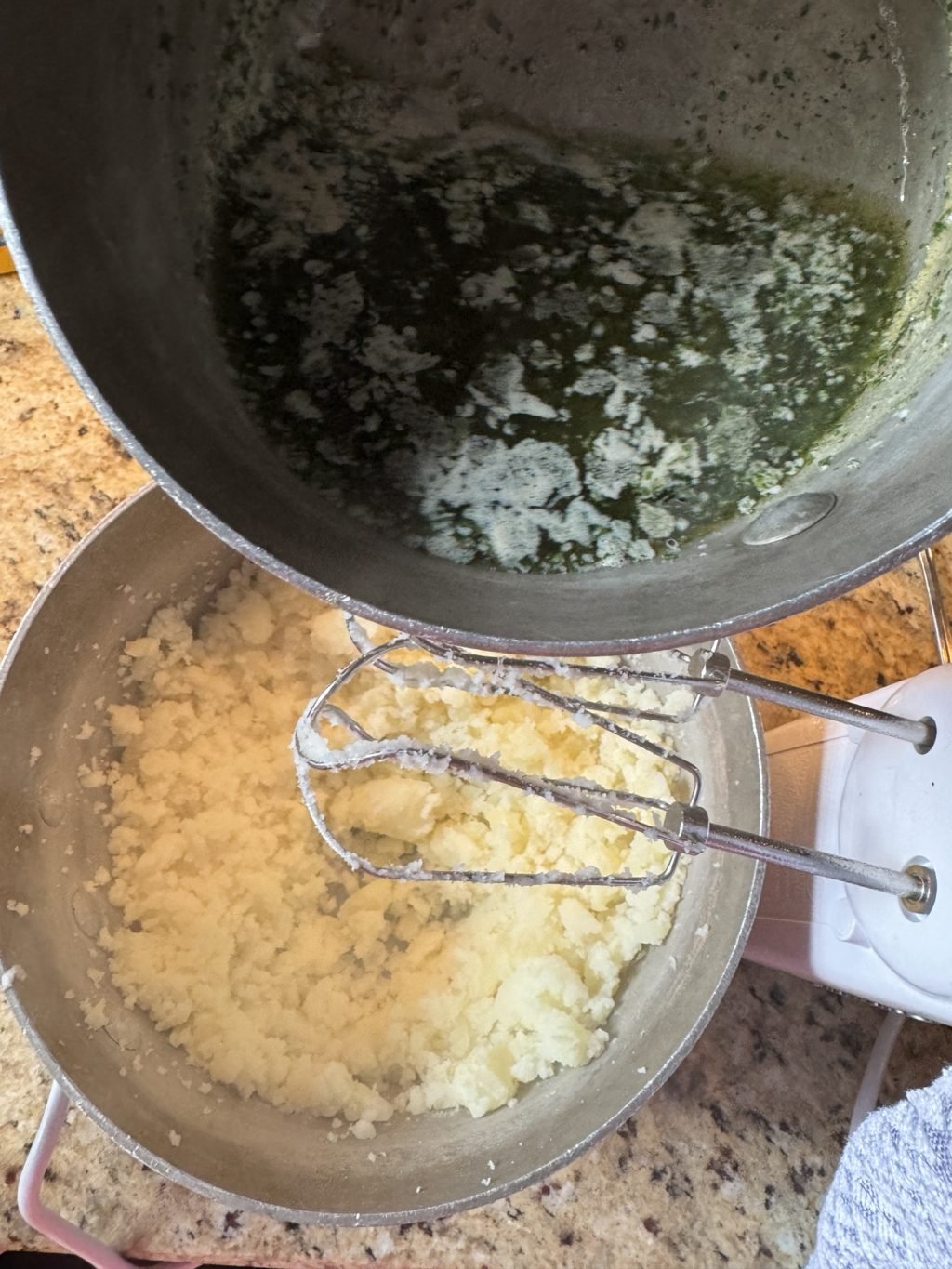 Melted herb butter being poured into mashed potatoes