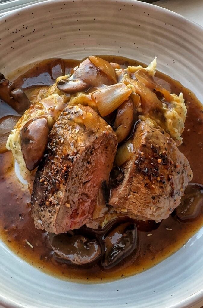 Steak over potatoes, mushrooms, and onions
