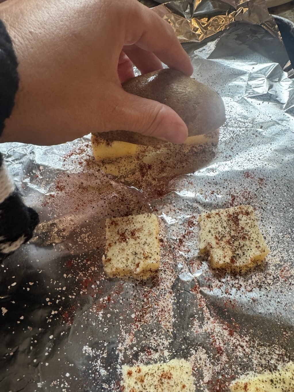 A potato half being pressed into seasoned butter pats