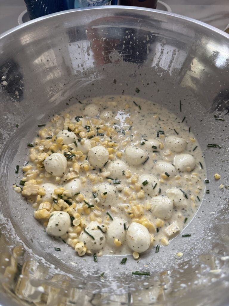 The cheese, corn, and seasonings in a metal bowl