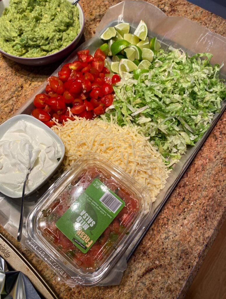 Various nacho toppings, like shredded lettuce, sour cream, and shredded cheese