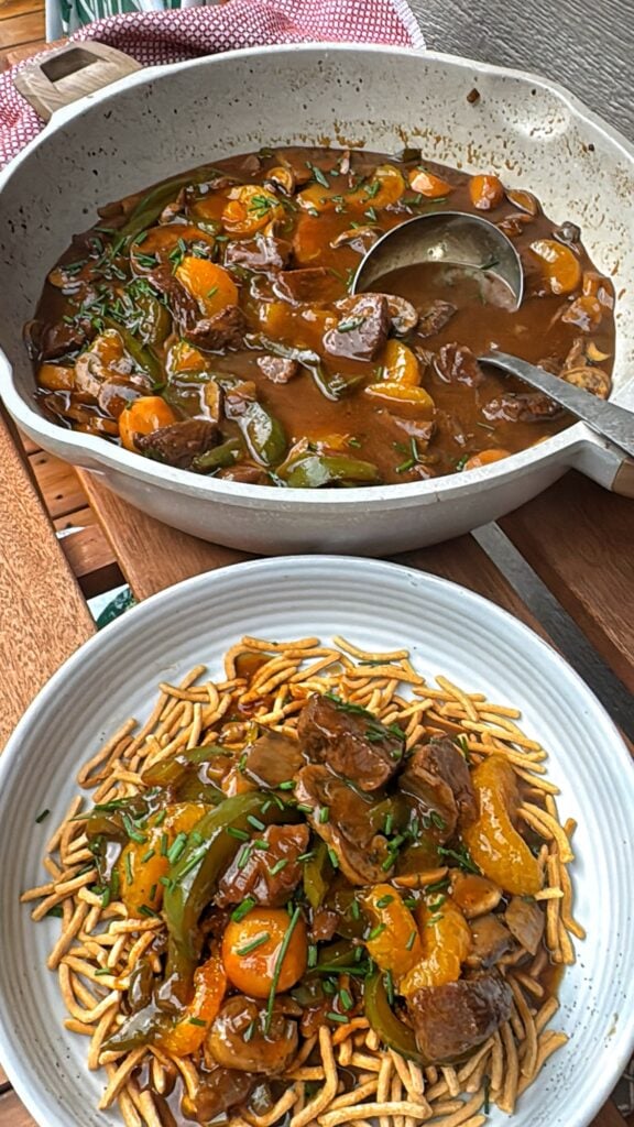 The finished dish on a plate in front of a pot of the beef