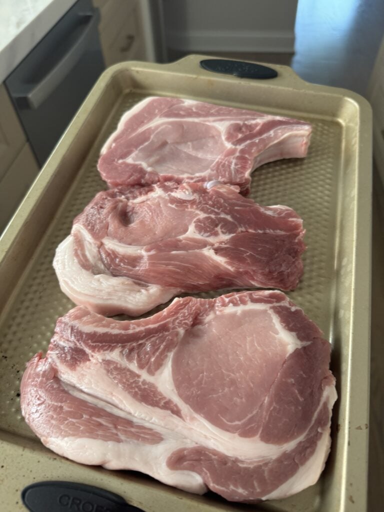 Raw pork chops on a baking pan