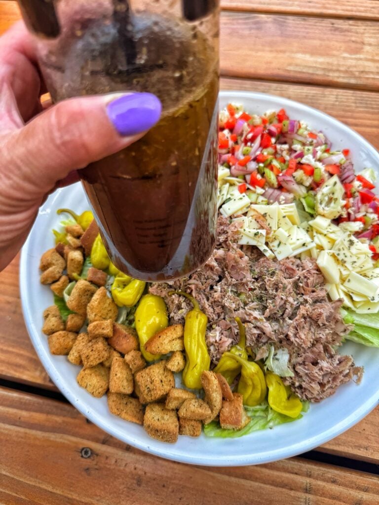 A container of dressing held over the salad