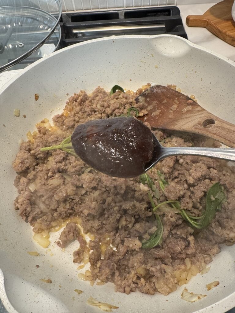 A spoon of Better Than Bouillon over the meat mixture
