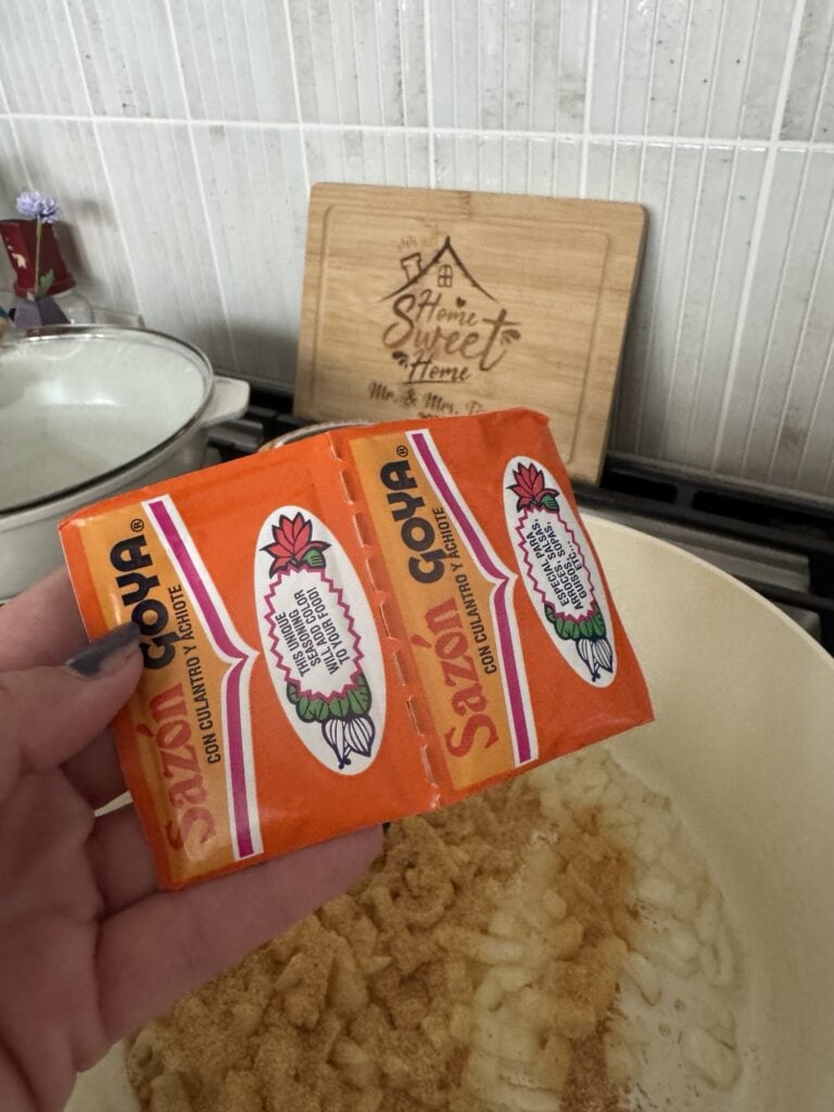 Sazon Goya seasoning being spread over potatoes in the pan