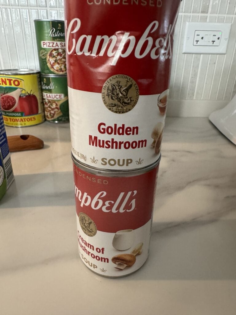 Two cans of Cambell's Mushroom Soup, one "Golden" and one "Cream of"