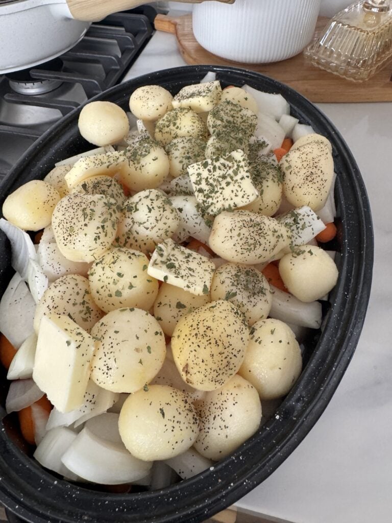 Potatoes, butter, onions, and carrots in the roaster before cooking