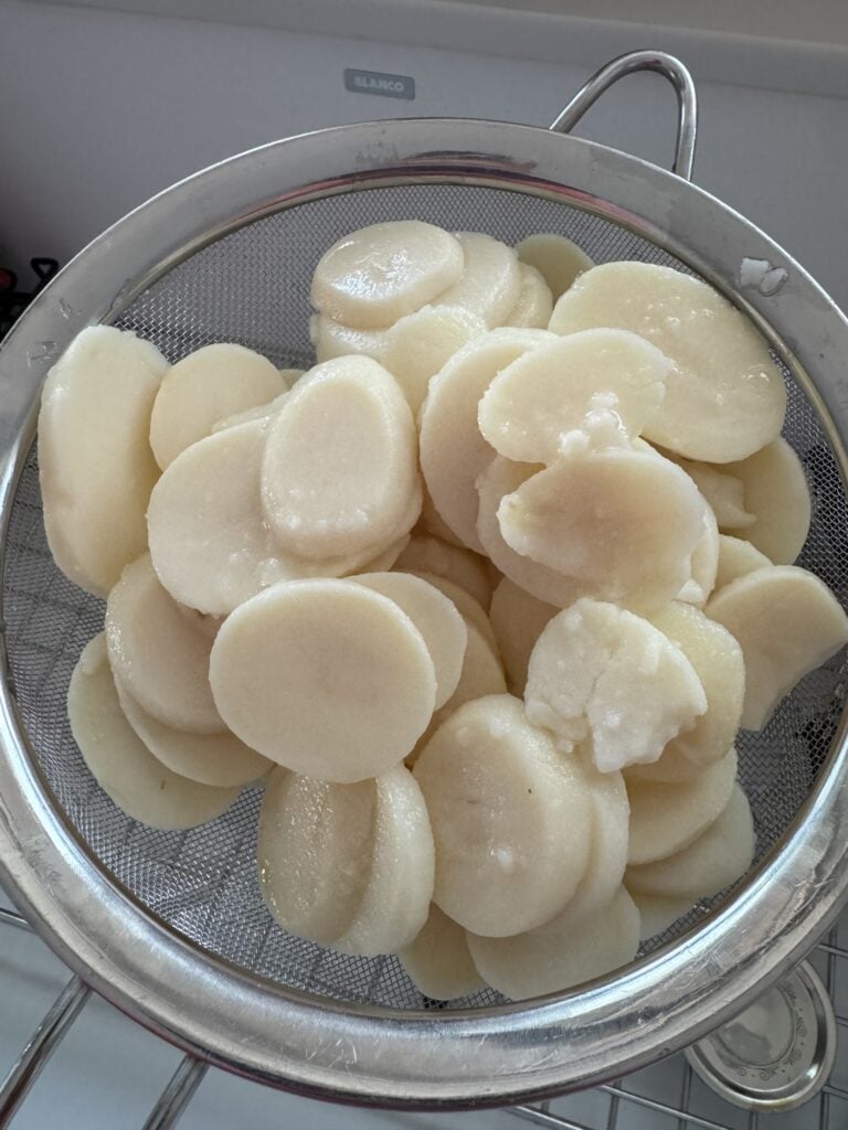 Sliced potatoes in a strainer