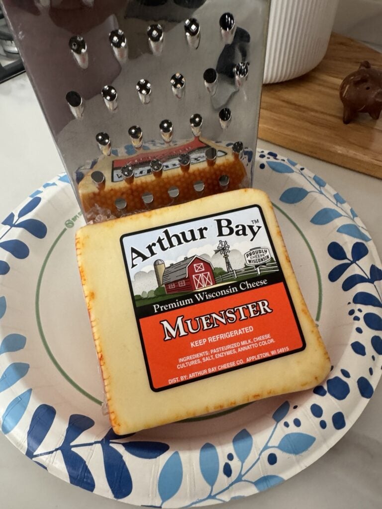 A cheese grater and package of Muenster cheese