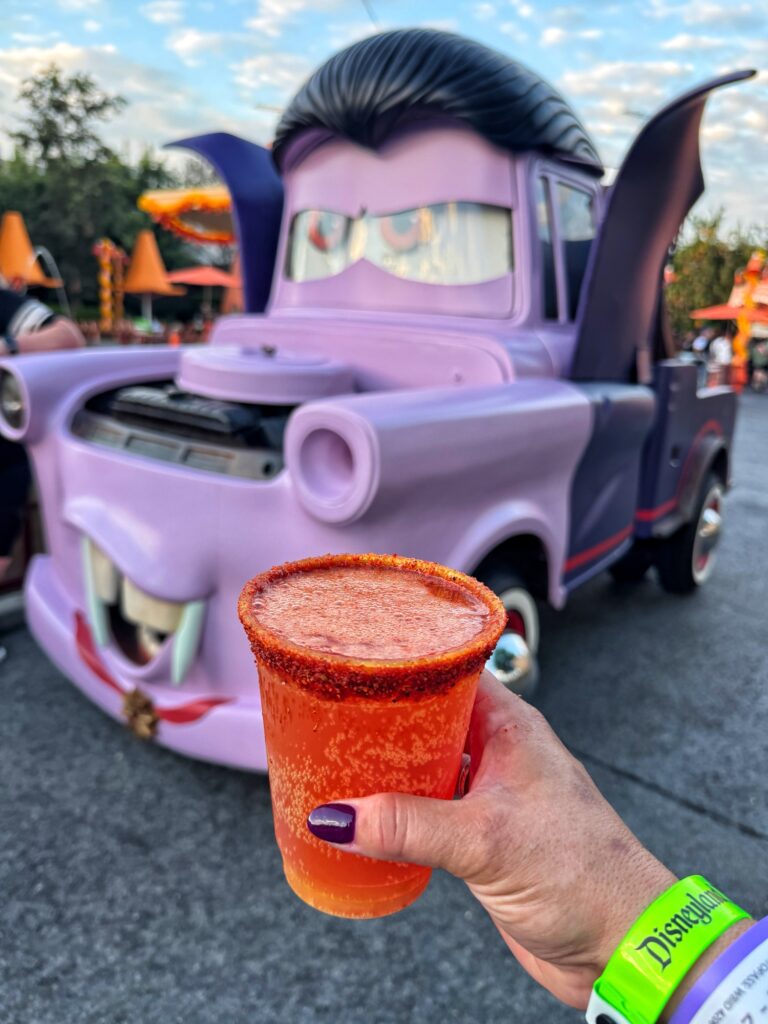 The watermelon cocktail held in front of a car dressed as a vampire