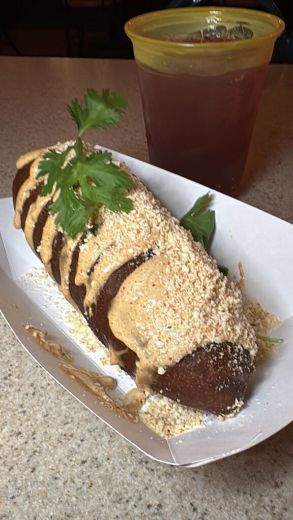 Fried corn on the cob next to a sangria seltzer