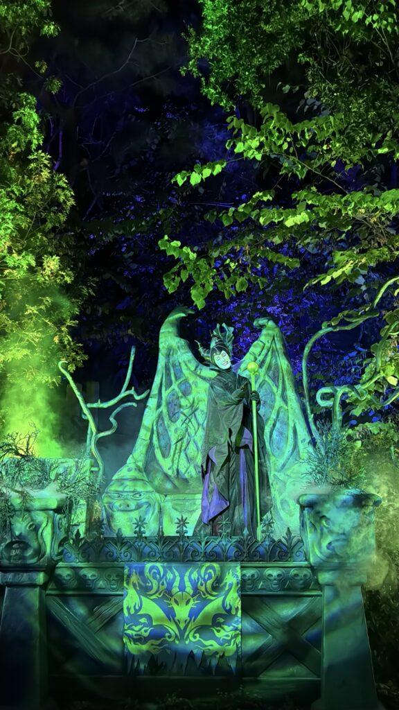 Maleficent standing on a spooky podium