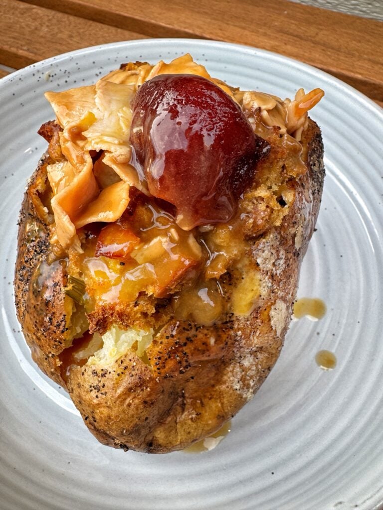 A baked potato stuffed with turkey, gravy, stuffing, and cranberry sauce