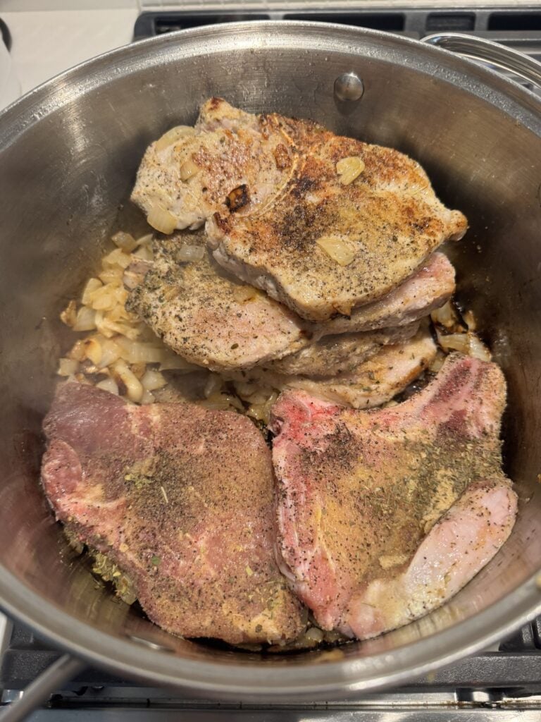 The pork chops in a bowl with chopped onions and garlic
