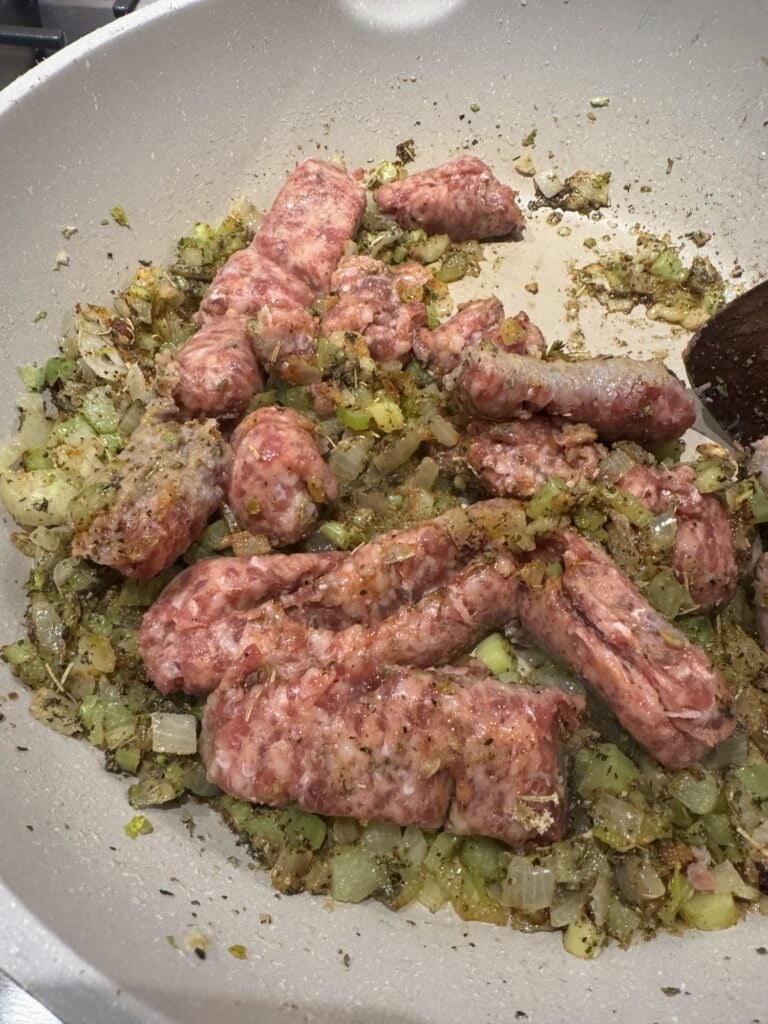 Italian sausage in the pan with diced onions and celery.