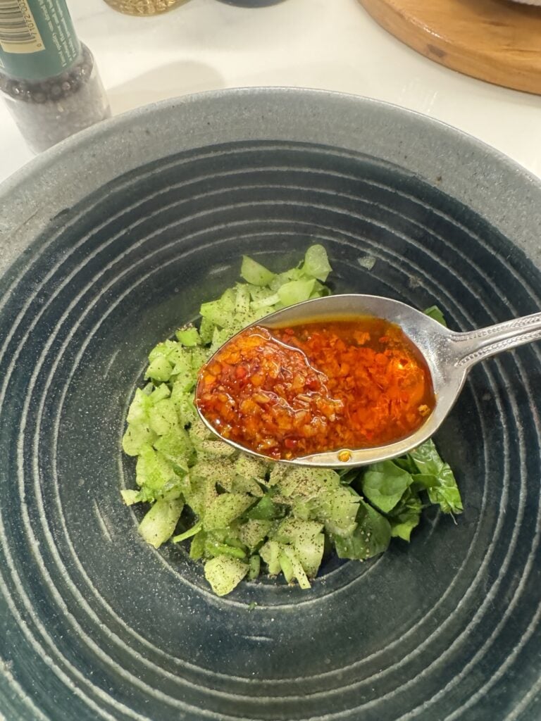 A spoon of chili crunch over diced greens