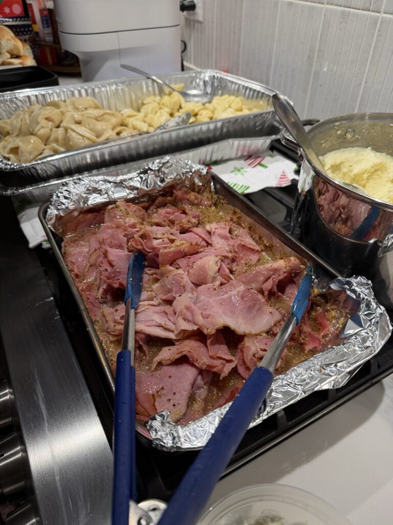 The finished ham on the stove with other party sides