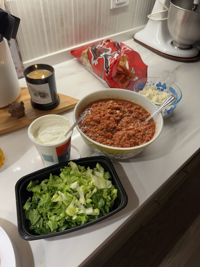 Sour cream, lettuce, cheese, and beef mixture set out as a tostada bar