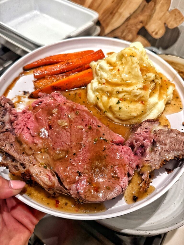 A side of honey roasted carrots next to mashed potatoes and prime rib