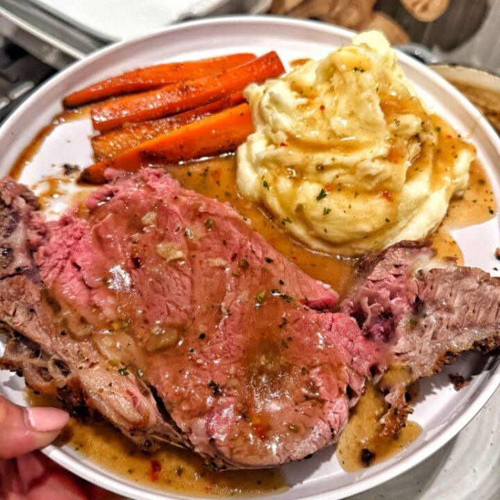 A side of honey roasted carrots next to mashed potatoes and prime rib