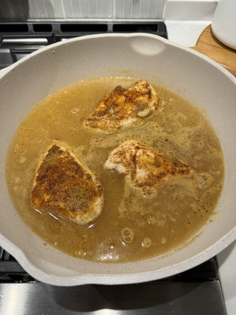 Seasoned chicken simmering in the pan