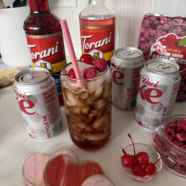 The finished drink surrounded by cans of Diet Coke and bottles of raspberry syrup