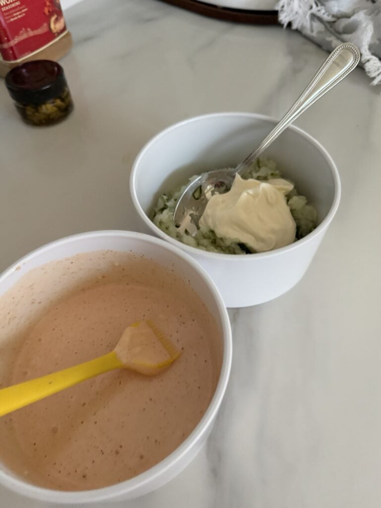 The two sauce mixtures in different containers, one with a spoon and one with a brush