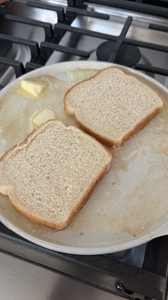 Slices of bread toasting in a pan of melted butter