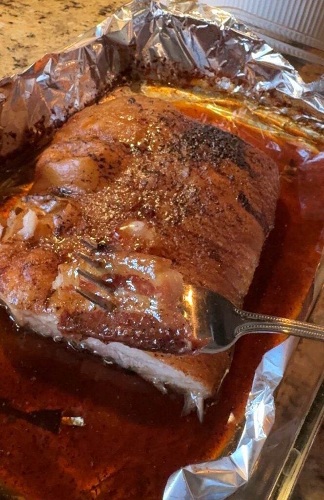 The finished pork belly with a chunk of the crispy fat on a fork