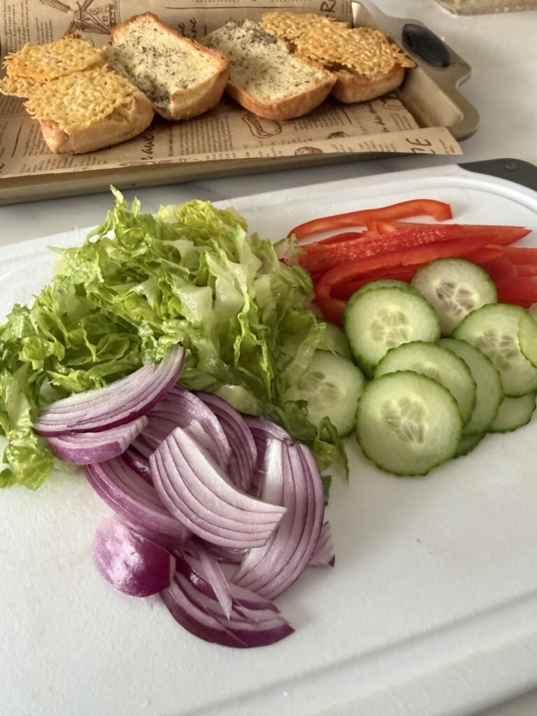 Cut up veggies in front of split sub bread