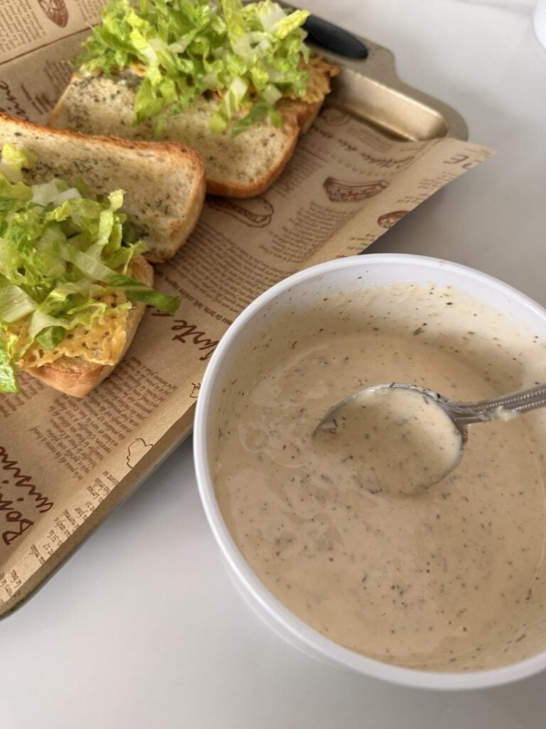 Two split sub rolls with shredded lettuce next to a bowl of white sauce
