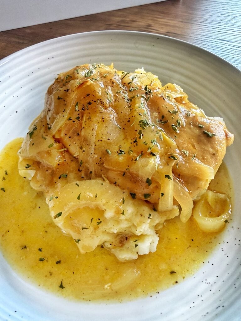 A finished piece of the chicken and gravy over mashed potatoes