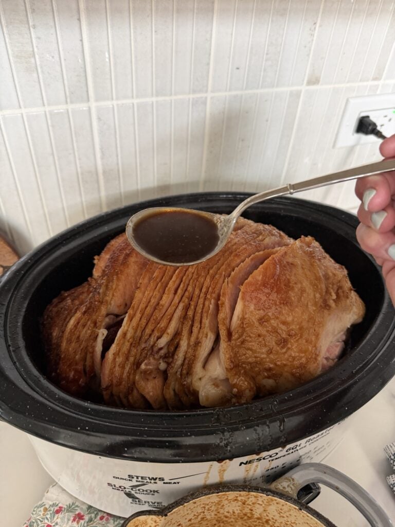 A spoon of glaze over sliced ham in the Nesco roaster