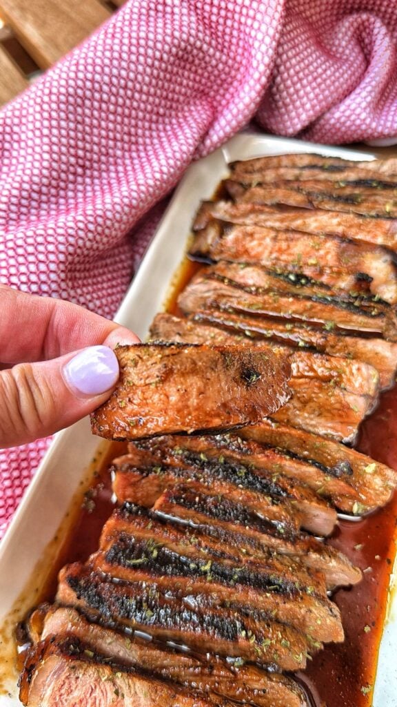 A piece of the steak being held up above other slices