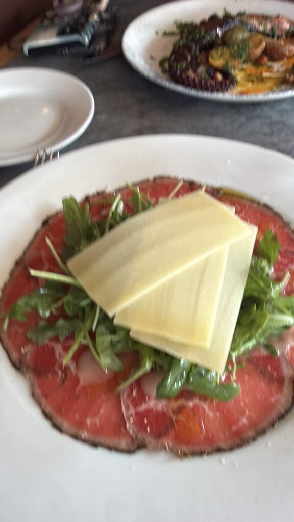 Wagyu been topped with greens, dressing, and cheese