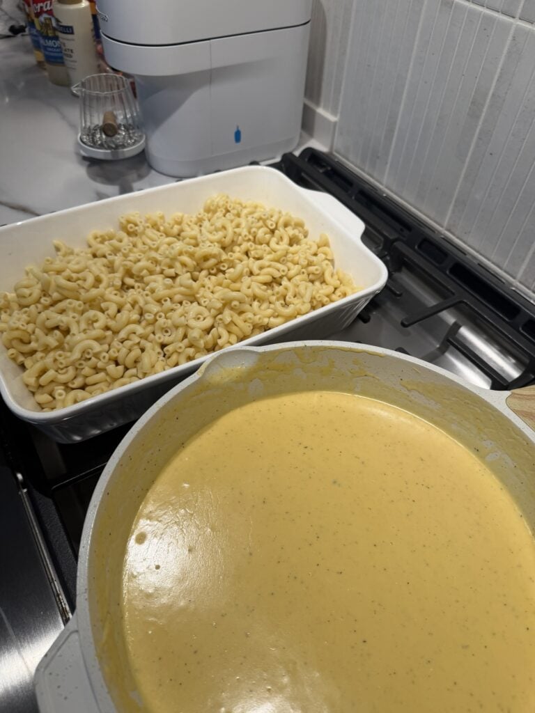 Macaroni in a baking dish behind a pan of cheese sauce