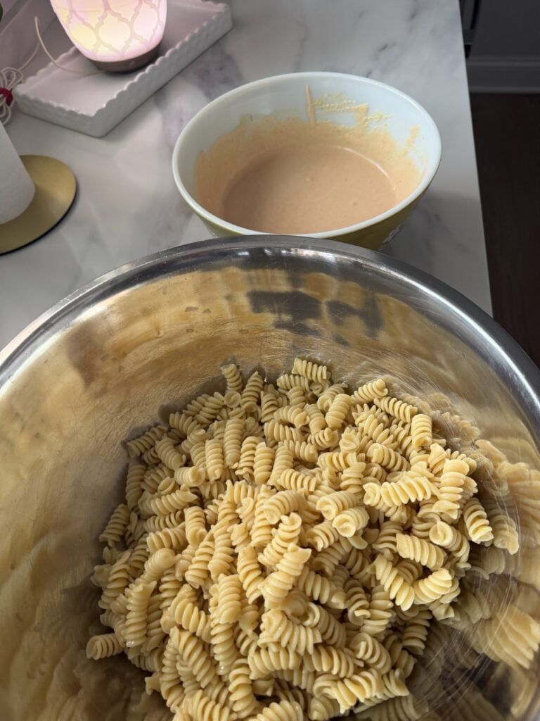 Pasta salad in a bowl next to dressing