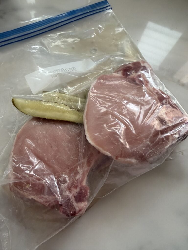 Raw pork chops and pickle spears in a zip-top bag 