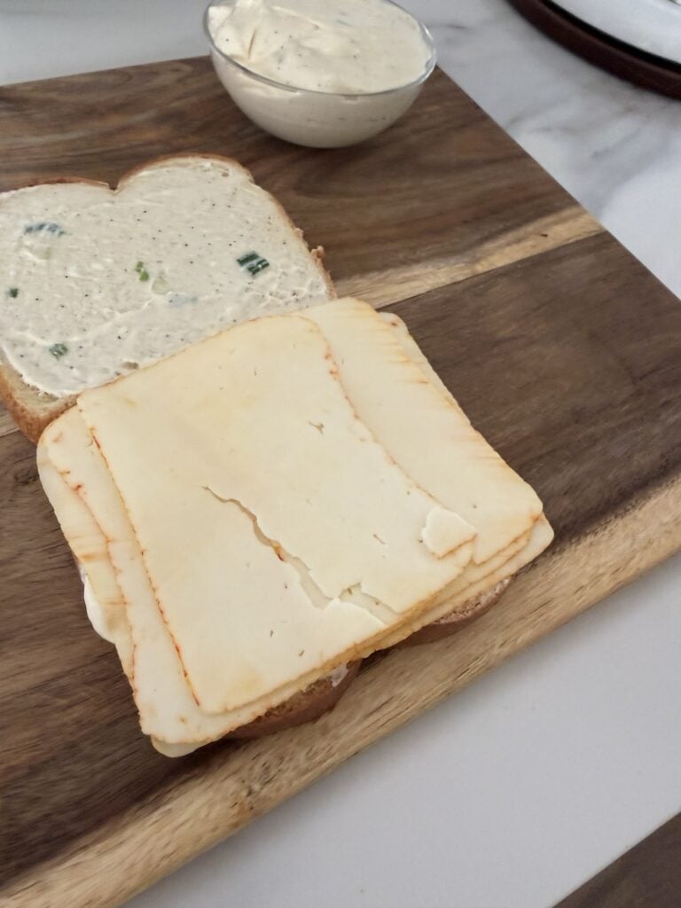 Layers of cheese on bread next to another slice of bread with the celery salt spread