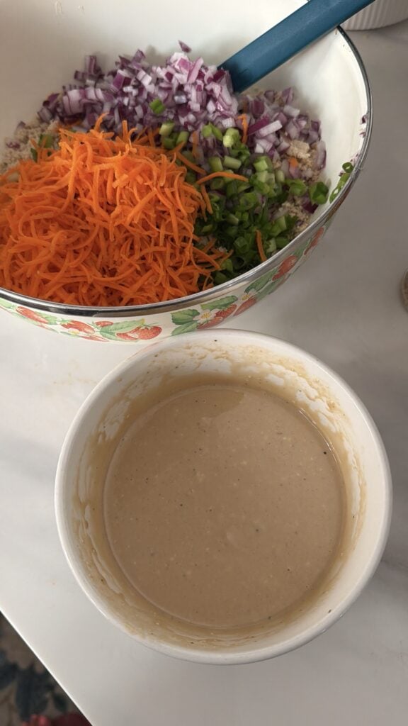 The chopped up veggies in a bowl next to a bowl of dressing