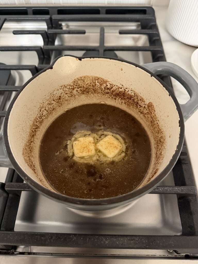 Two pats of butter melting into the pan sauce