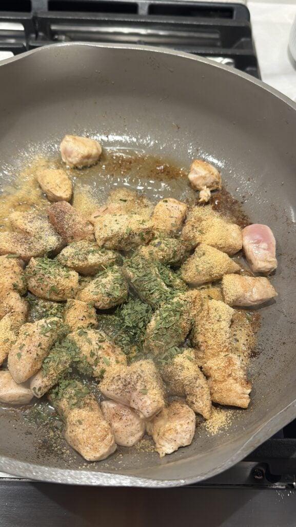 Chicken and seasonings cooking in the pan