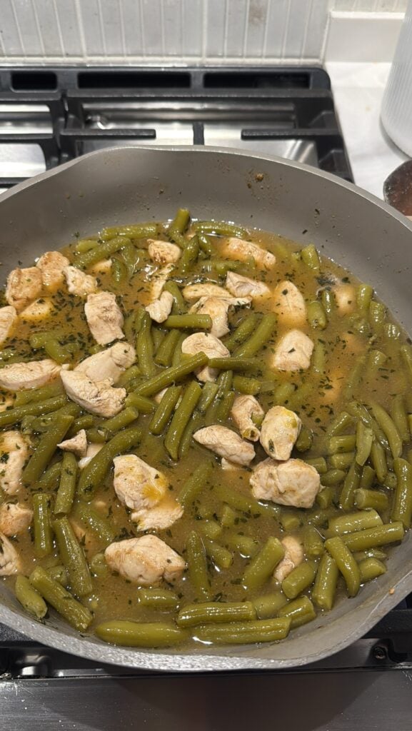 The chicken and green beans cooking in the pan