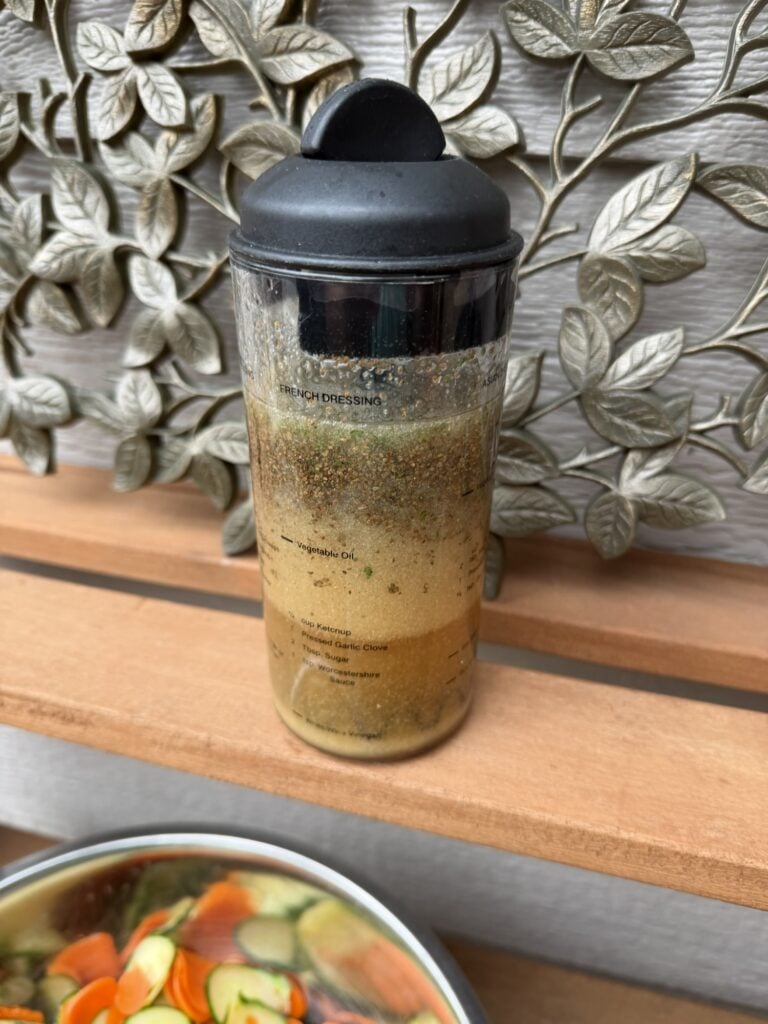 The dressing in a reusable bottle tumbler next to the salad