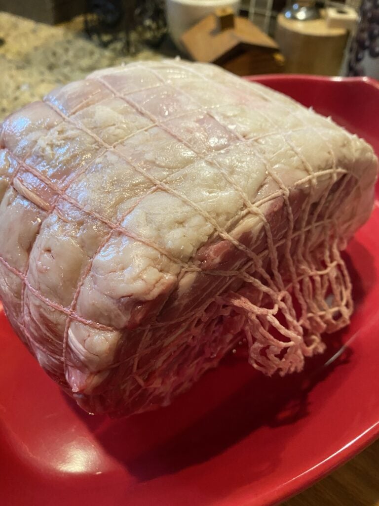 Bone-in rib roast with butcher netting holding the partially cut roast against the rib bones.